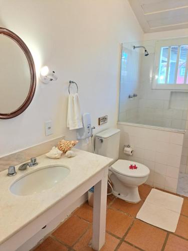a bathroom with a sink and a toilet and a mirror at Pousada dos Pássaros Geribá in Búzios