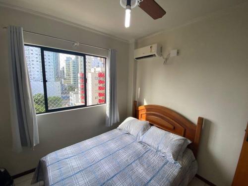 - une chambre avec un lit et une fenêtre dans l'établissement AP de praia com sacada, churrasqueira e garagem, à Balneário Camboriú
