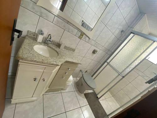 La salle de bains blanche est pourvue d'un lavabo et de toilettes. dans l'établissement AP de praia com sacada, churrasqueira e garagem, à Balneário Camboriú