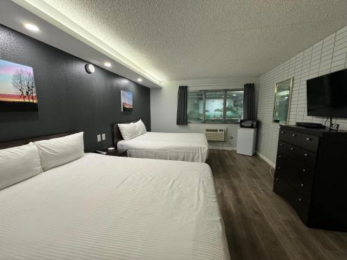 a hotel room with two beds and a flat screen tv at Travelodge by Wyndham Winnipeg in Winnipeg