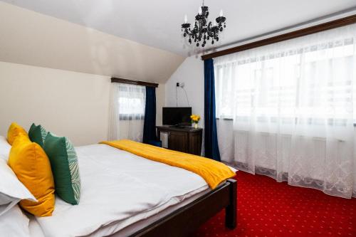 a bedroom with a bed with yellow sheets and a window at VILA LUCA-Hotel in Şirnea