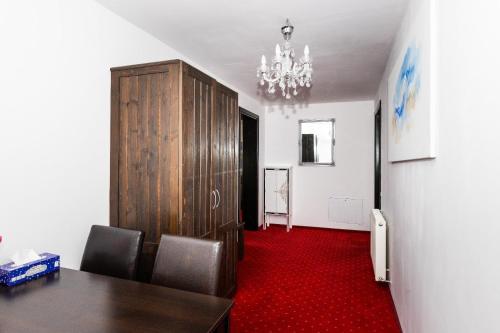 a dining room with a table and a cabinet and red carpet at VILA LUCA-Hotel in Şirnea