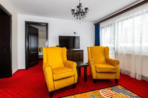 two yellow chairs and a table in a room at VILA LUCA-Hotel in Şirnea