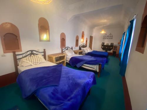 a room with three beds with blue comforters in it at Tafsut dades guesthouse stay with locals in Tamellalt