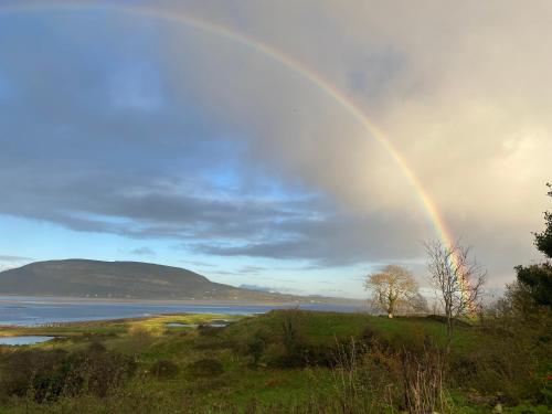 ein Regenbogen am Himmel über einem Gewässer in der Unterkunft Curlew Cottage in Beltra
