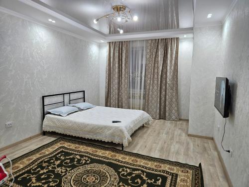 a bedroom with a bed and a television and a rug at 2 комнатная квартира in Aktobe