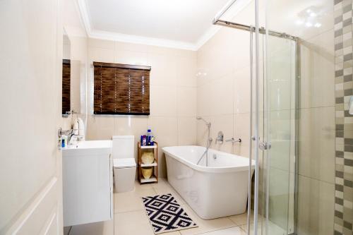 a white bathroom with a tub and a shower at URlyfstyle 5 bedrooms 10km from OR Tambo Int Airport in Kempton Park