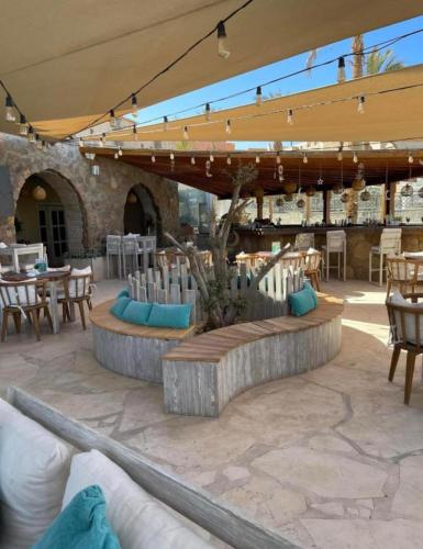 a patio with tables and chairs and a bench and tables at Azzura appartment sahl hashesh with private garden in Hurghada