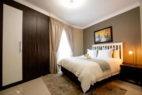 a bedroom with a bed with a teddy bear on it at URlyfstyle 5 bedrooms near OR Tambo international Airport in Kempton Park