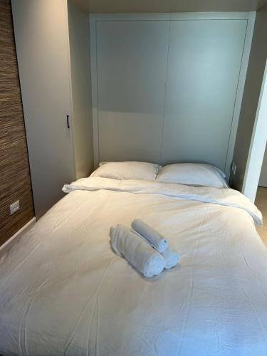 Una toalla blanca sobre una cama blanca en דירת נופש בהרצליה en Herzliyya B