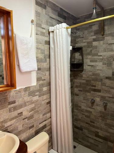 a bathroom with a shower with a white shower curtain at El Encanto de Mimi in Puerto Ayora
