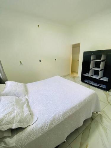 a bedroom with a large white bed with white sheets at Casa em Bombinhas in Bombinhas