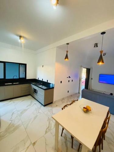 a living room with a table and a kitchen at Casa em Bombinhas in Bombinhas