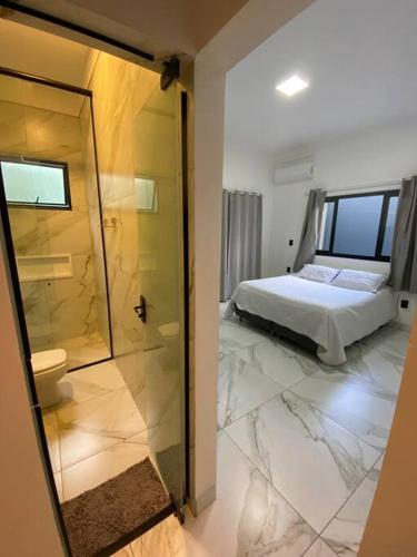a bedroom with a bed and a bathroom with a shower at Casa em Bombinhas in Bombinhas