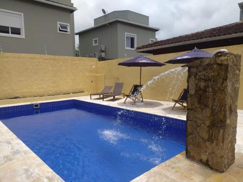 a swimming pool with two umbrellas and a fountain at Pousada Villa Encanto in Juquei
