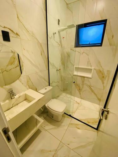 a bathroom with a toilet and a tv on the wall at Casa em Bombinhas in Bombinhas