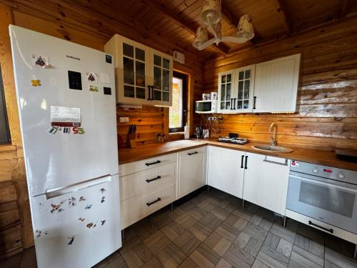eine Küche mit einem weißen Kühlschrank und Holzwänden in der Unterkunft Ranczo Targoszów in Targoszów