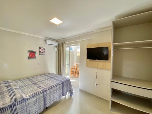 a bedroom with a bed and a tv in a room at Ondas do Mar Residencial in Bombinhas