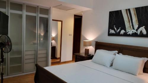 a bedroom with a white bed and a mirror at Sea View Monarch Apartment located within Cinnamon Grand Hotel Complex in Colombo