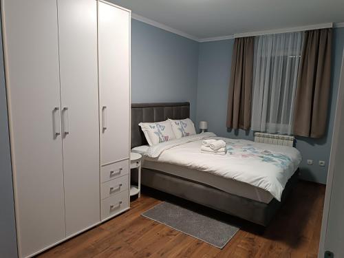 een slaapkamer met een bed en een witte kast bij Apartman Jela in Borča