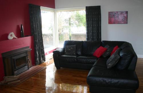 un sofá de cuero negro en una sala de estar con chimenea en Banksia Cottage, en Albury