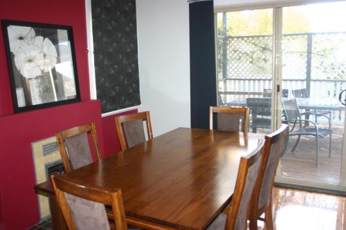 uma sala de jantar com uma mesa de madeira e cadeiras em Banksia Cottage em Albury