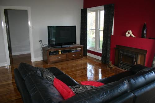 sala de estar con sofá y TV en Banksia Cottage, en Albury