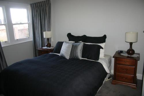 a bedroom with a large bed and two windows at Banksia Cottage in Albury