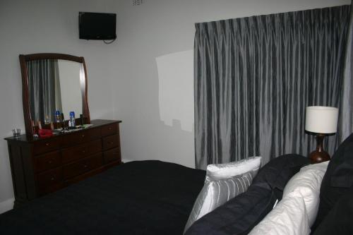 a bedroom with a couch and a mirror and a dresser at Banksia Cottage in Albury