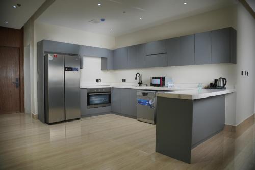 una cucina con elettrodomestici in acciaio inossidabile e armadietti grigi di شقة فندقية Elite Corner a Riyad
