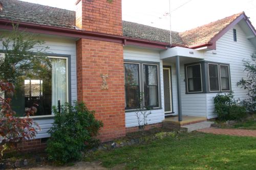 a brick house with a dog sitting in the window at Banksia Cottage in Albury
