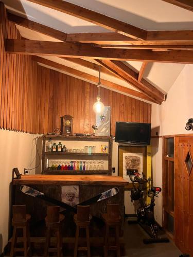 un bar en una habitación con paredes de madera y taburetes de madera en Casa para 9 personas a 30 metros del lago Caburgua ! en Caburga