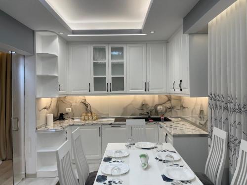 a kitchen with white cabinets and a table and chairs at Vila Mete Apartment's in Korçë