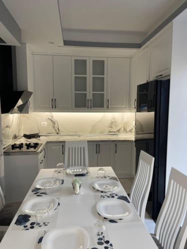 een witte keuken met een tafel met stoelen en een tafel bij Vila Mete Apartment's in Korçë