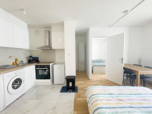Cet appartement blanc comprend un lit et une cuisine. dans l'établissement Cosy, simple, centrale, easy transport, à Asnières-sur-Seine