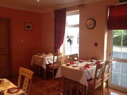 a dining room with two tables and a clock on the wall at Anvil House in Achill Sound