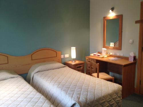 Habitación de hotel con 2 camas, escritorio y espejo. en Anvil House en Achill Sound