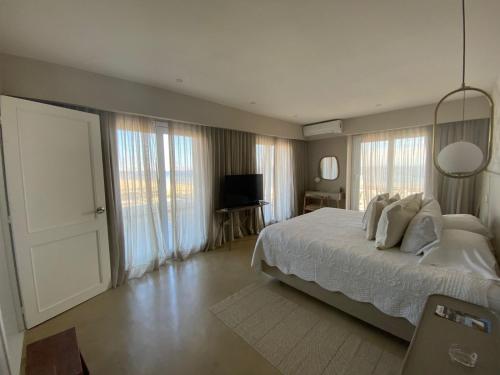 a bedroom with a bed with white sheets and windows at Serena Hotel - Punta del Este - Unico sobre la Playa in Punta del Este