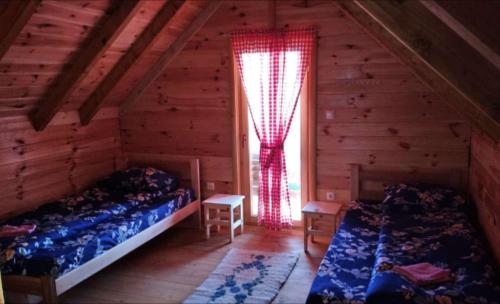 1 dormitorio con 2 camas y una ventana en una cabaña de madera en Cottages Jasavić, en Plav