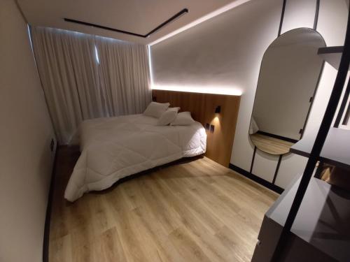um pequeno quarto com uma cama e uma televisão em Apartamento You Canela 207 em Canela