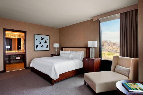 um quarto com uma cama, uma cadeira e uma janela em The Westin Birmingham em Birmingham