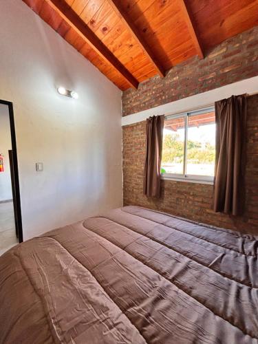 a bedroom with a large bed in a brick wall at Departamentos Merlina in El Hoyo
