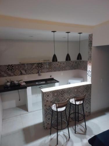 a kitchen with two bar stools and a counter at Hospedagem Central Eu Amo Piri in Pirenópolis