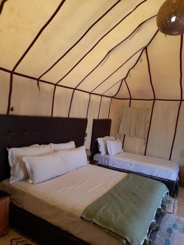 two beds in a room with a tent at Merzouga Highdune Camp With Heated Tents in Merzouga