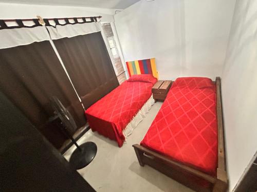 2 camas en una habitación pequeña con sábanas rojas en Wayta “Casa de campo” en San Fernando del Valle de Catamarca