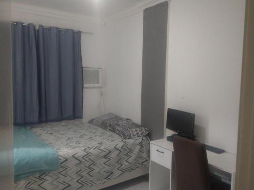 um pequeno quarto com uma cama e uma televisão em 2 quadras do mar em Vila Velha