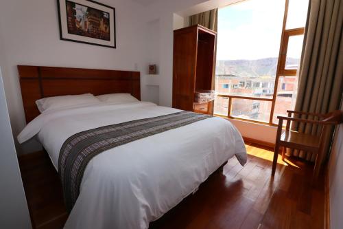 sypialnia z białym łóżkiem i dużym oknem w obiekcie El SOL HOTEL - URUBAMBA w mieście Urubamba