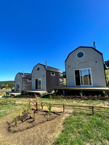 a couple of houses sitting on top of a field at Dalcahue Lodge 