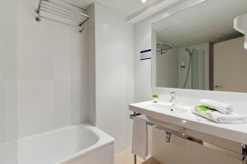 a bathroom with a sink and a tub and a mirror at Santa Limbania Boutique Hotel in Santa Cruz de la Sierra