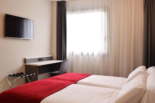 a hotel room with a bed and a desk and a window at Santa Limbania Boutique Hotel in Santa Cruz de la Sierra